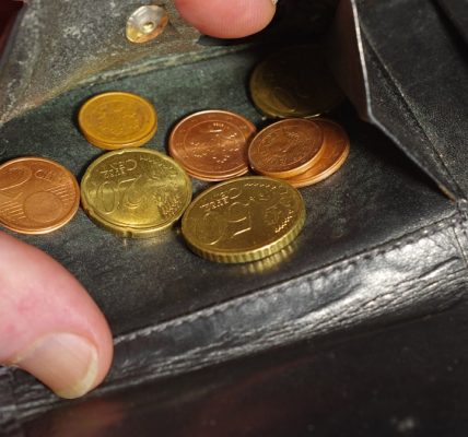 Hand placing coins into a black leather wallet.