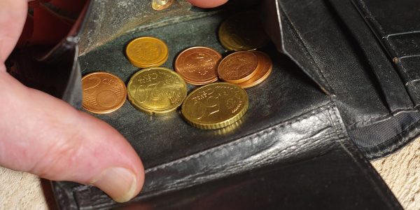 Hand placing coins into a black leather wallet.